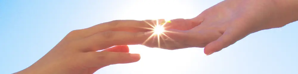 Hands reaching out with sunlight between, symbolizing hope and connection in mental health support.