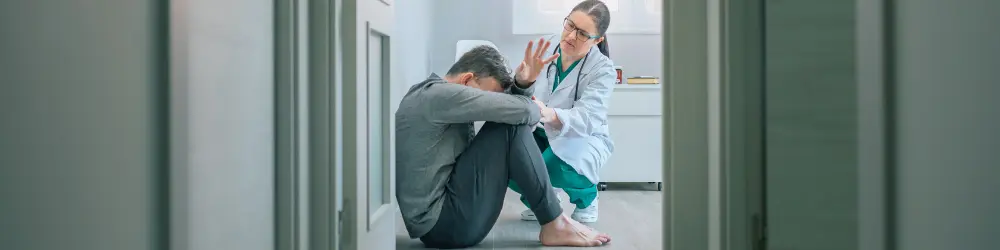 Doctor providing mental health support to a patient sitting on the floor.