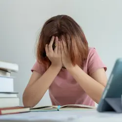 Mental health crisis support - overwhelmed individual with head in hands surrounded by books